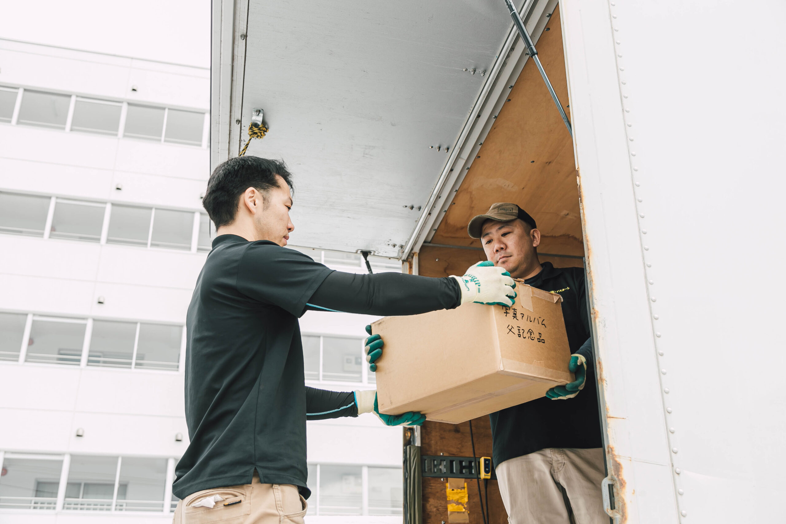 札幌で不用品回収作業を行うスタッフがトラックに段ボールを積み込む様子|ゴミ屋敷片付けや一軒家丸ごと清掃にも即日対応