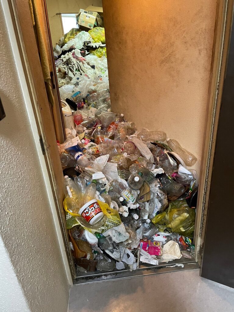 札幌のゴミ屋敷片付け前の廊下と部屋。大量のペットボトルや不用品で通路がふさがれた状態