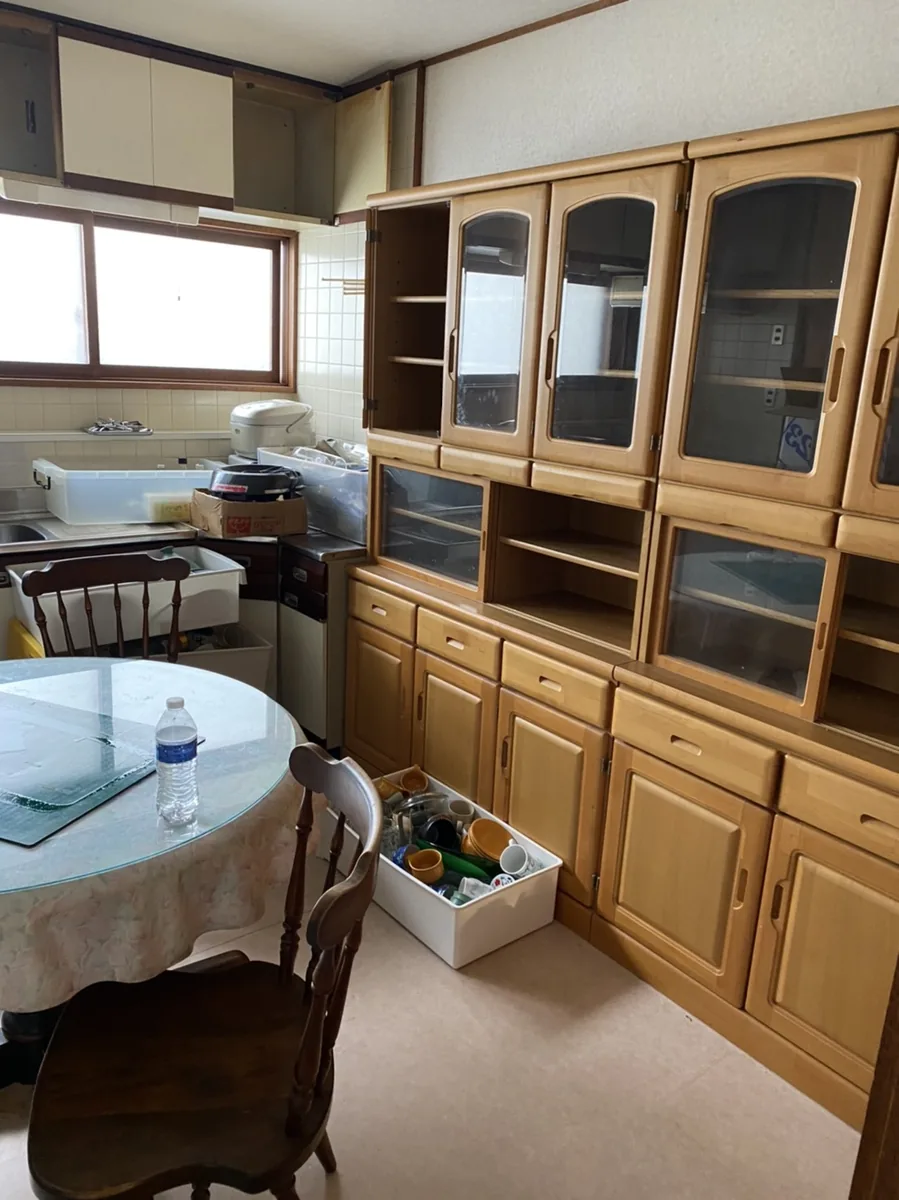 札幌市西区の遺品整理ビフォー - キッチンに大型食器棚やテーブルが残された状態